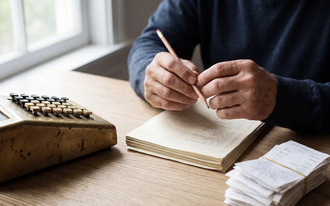 Mains qui pointent des écritures à côté d'une calculatrice